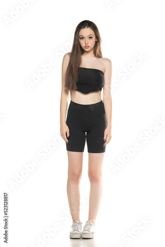 Young woman in black shorts and top posing in the studio on white. © vladimirfloyd