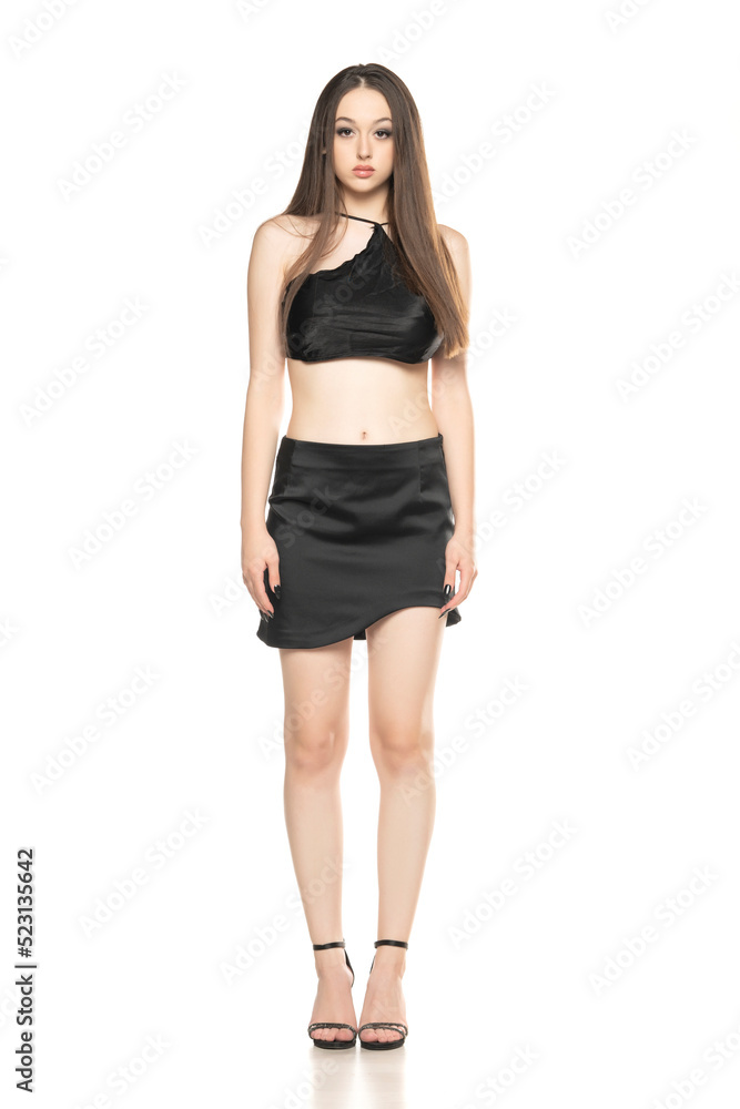 Young woman with short, black summer skirt and top, posing in the studio on white Young woman with short, black summer skirt and top, posing in the studio on white