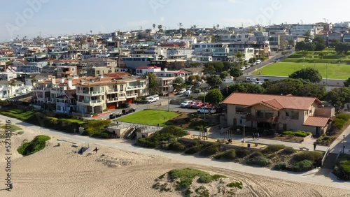 Aerial: Panning Shot Of Cars Parked Outside Houses In City, Drone Flying Over Beach On Sunny Day - Manhattan Beach, California