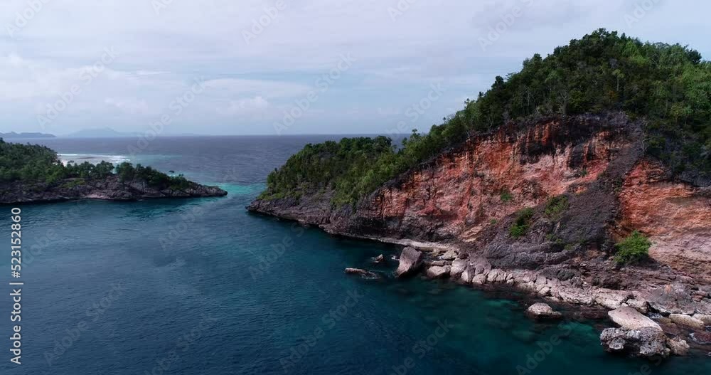 Aerial shot of tropical island with patch of red rocks and turquoise water