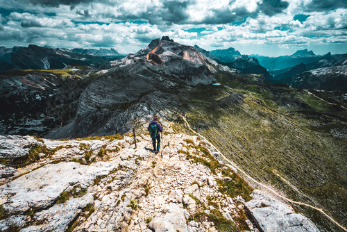Young woman is hiking on beautiful trail Seekofel to Baires Lake in the Dolomite mountains in the afternoon. Seekofel , Dolomites, South Tirol, Italy, Europe.