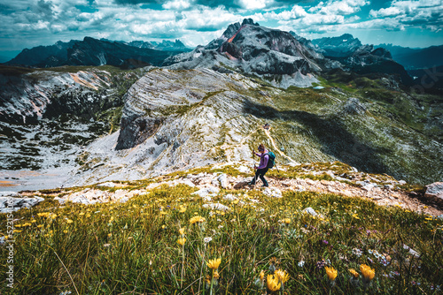 Young woman is hiking on beautiful trail Seekofel to Baires Lake in the Dolomite mountains in the afternoon. Seekofel , Dolomites, South Tirol, Italy, Europe. photo