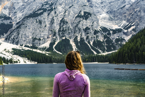 Young woman enjoys beautiful view on Baires Lake in the Dolomite mountains in the afternoon. Braies Lake (Pragser Wildsee, Lago di Braies), Dolomites, South Tirol, Italy, Europe.