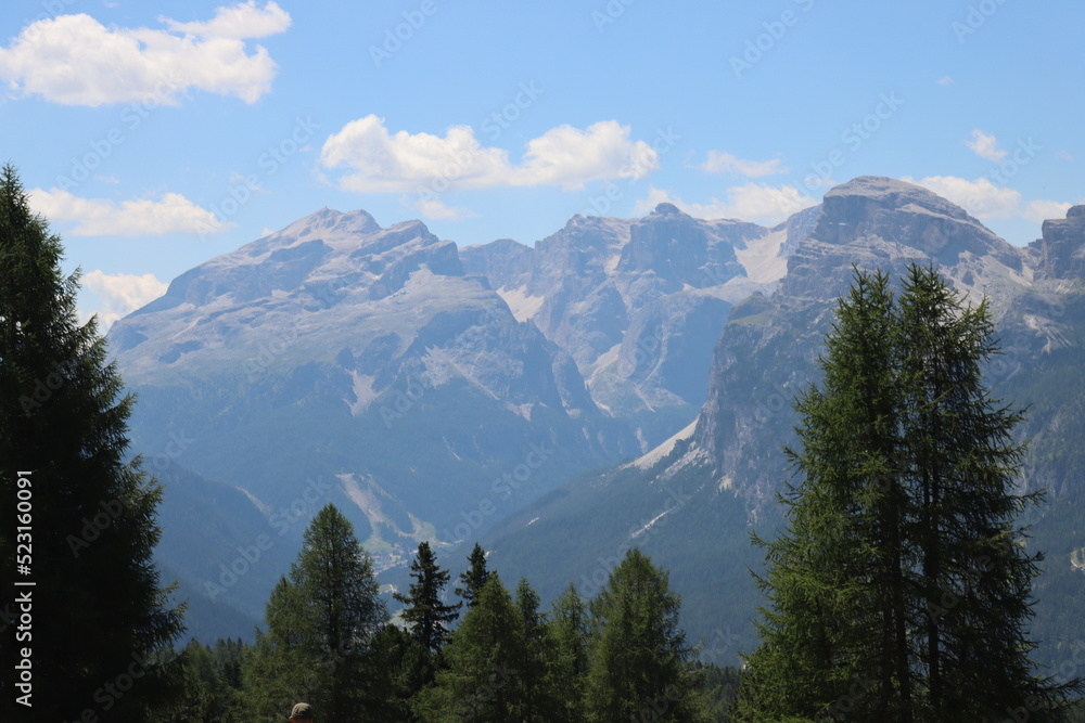 Val Badia, Italy-July 17, 2022: The italian Dolomites behind the small village of Corvara in summer days with beaitiful blue sky in the background. Green nature in the middle of the rocks. Val Badia, Italy-July 17, 2022: The italian Dolomites behind the small village of Corvara in summer days with beaitiful blue sky in the background. Green nature in the middle of the rocks.