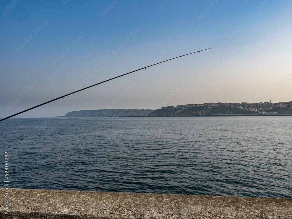 fishing rod over sky and blue sea fishing rod over sky and blue sea