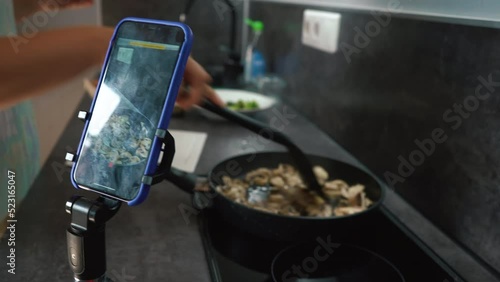 Chef blogger cooking meal and recording video for blog. Young woman cook and filming himself on smartphone for culinary blog while preparing healthy meal with vegetables in kitchen. 4k footage