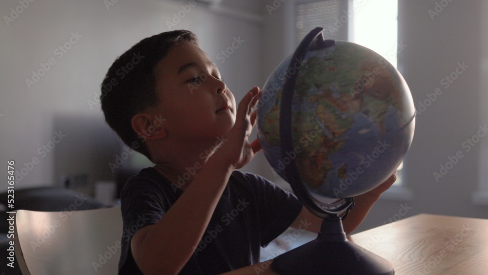 Naklejka premium Cute Preschooler explores countries on the globe