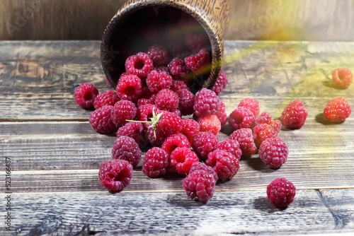Raspberries in a wooden glass on a wooden background