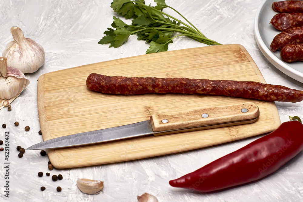 spicy smoked sausages on a cutting board next to red pepper garlic spices and herbs on the table spicy smoked sausages on a cutting board next to red pepper garlic spices and herbs on the table