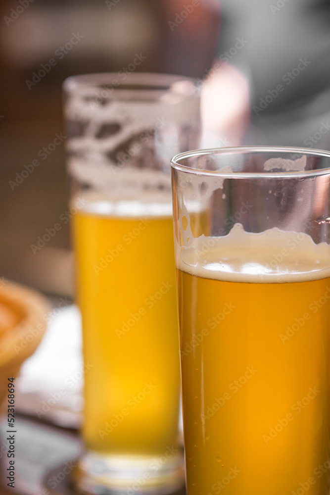 Two glasses of light beer with foam on table at a craft czech brewery. Weekend meeting with friends. Oktoberfest concept Two glasses of light beer with foam on table at a craft czech brewery. Weekend meeting with friends. Oktoberfest concept