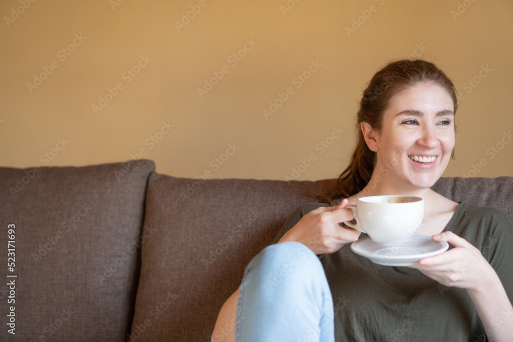 young red-haired girl smiling while drinking coffee young red-haired girl smiling while drinking coffee