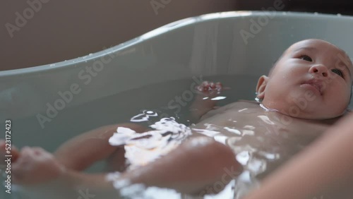 Cute baby having bath. Mother holds and bathes baby
