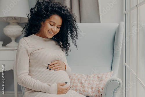 Obraz na plátně Happy beautiful pregnant woman in casual dress tenderly embracing belly