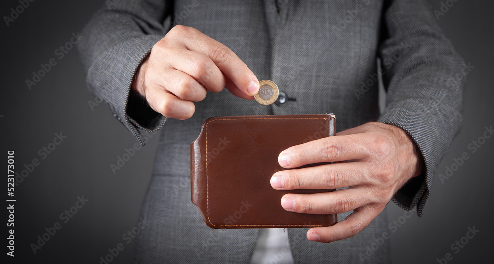 Obraz premium Man putting coin into his wallet.