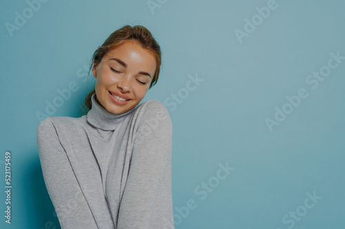 Pleased tender woman keeps eyes closed smiles tenderly recalls nice moment from life