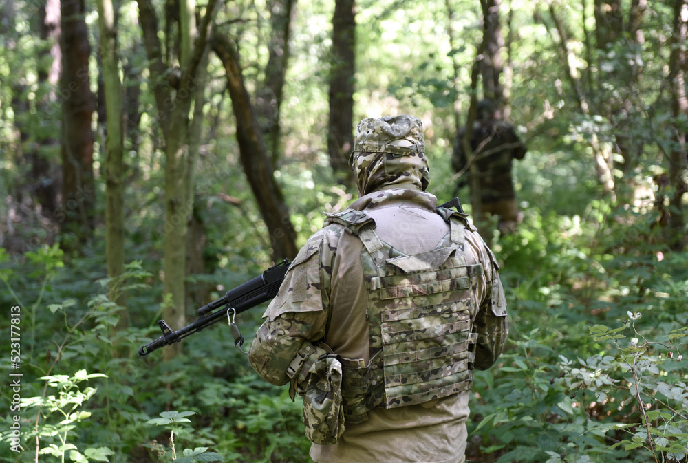 Soldiers with assault rifle in forest. Soldiers during combat. Tactical exercises. War in Ukraine