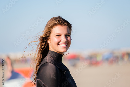 Portrait of kite surfing girl smiling in swimsuit with kitesurf on the beach. Water sports, and sporty woman concept © damianobuffo