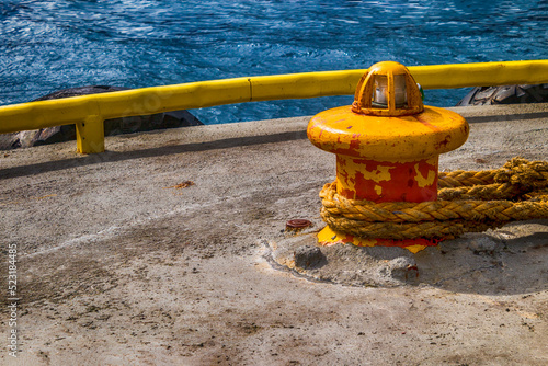 Yellow bollard and hawser on pier