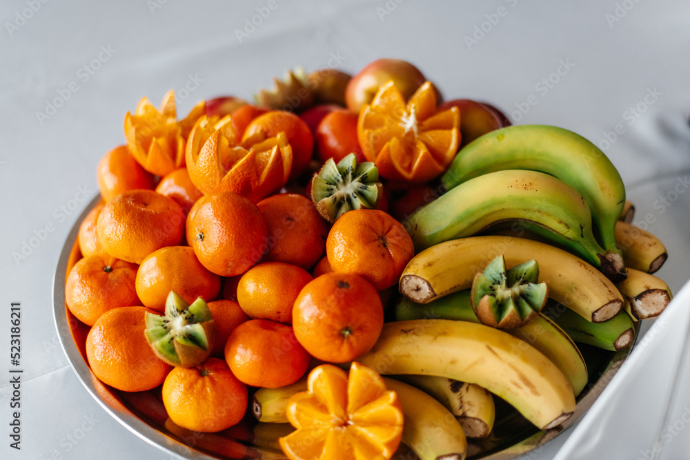 A beautifully arranged fruit platter with bananas, oranges, and carved pineapples. A beautifully arranged fruit platter with bananas, oranges, and carved pineapples.