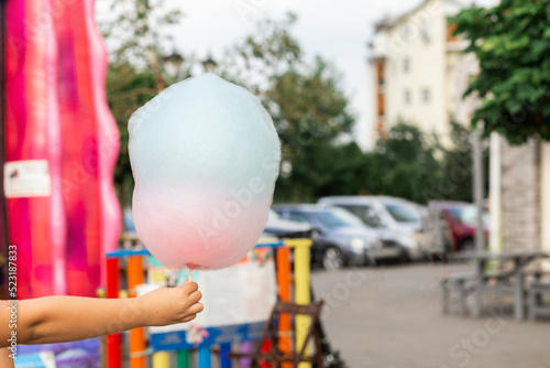 cotton candy in a child's hand on a blurred background of the street