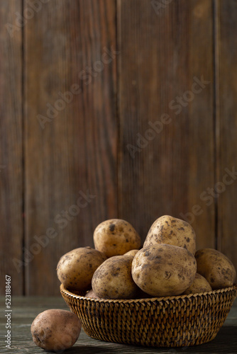 Close-up of fresh uncooked potato roots in a basket on wooden table copy space