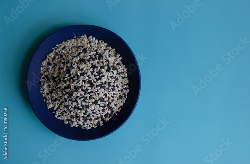 White and black sesame seeds on a blue plate.