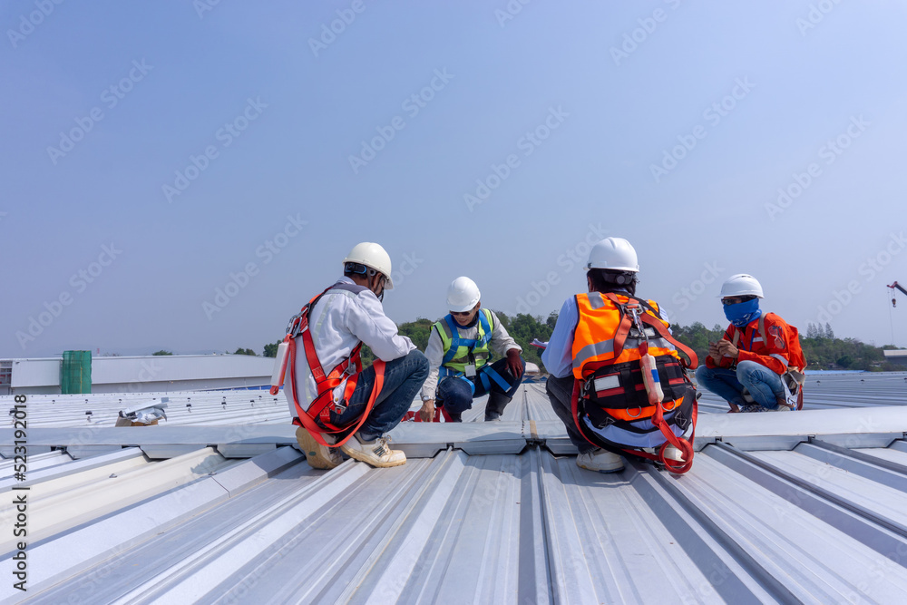 Team engineers wearing full safety body harness working on roof top for