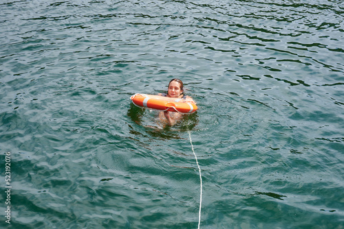 A Hispanic attractive young woman swimming in the water in a lifebuoy