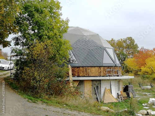 Non traditional spherical dome house constructed from wooden triangles, presenting geodesic architecture, sustainable design approach, and innovative residential building concept.