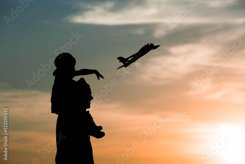 Father and son launch a toy airplane at sunset. Silhouettes of people against the sky. The concept of a friendly family and Father's Day. Air tour. Go on a trip, a flight and a vacation.