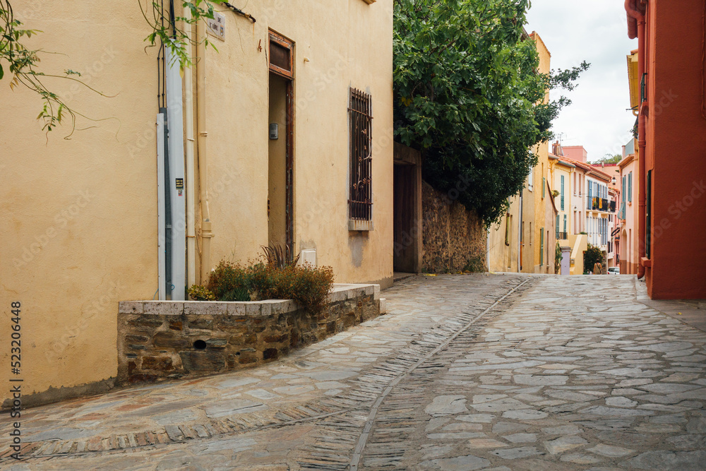 Naklejka premium Une vieille rue pavée dans un village de France. Une rue de Collioure. Des maisons colorées dans un village de Catalogne.