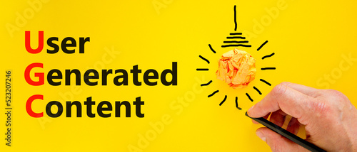 UGC user generated content symbol. Concept words UGC user generated content on a beautiful yellow background. Orange light bulb icon. Business and UGC user generated content concept. Copy space. photo