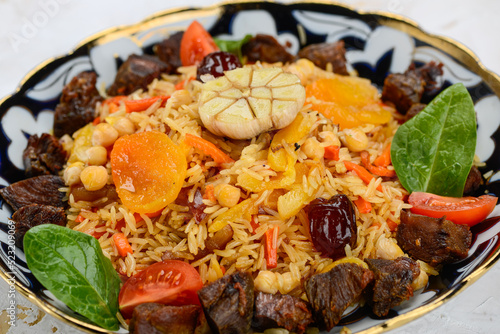 pilaf with meat, plum and apricot in a painted plate, macro photo 