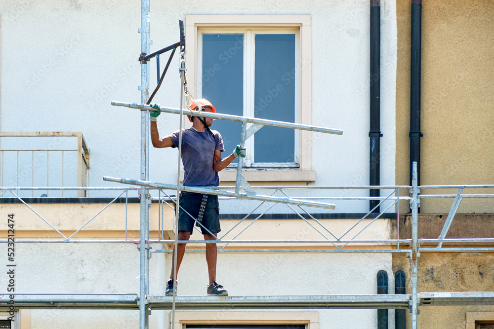 workers in safety uniform install reinforced steel scaffolding to renovate a facade in Geneva, Switzerland