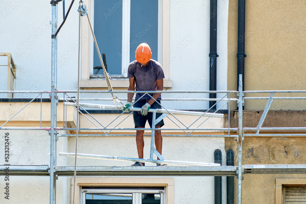 workers in safety uniform install reinforced steel scaffolding to renovate a facade in Geneva, Switzerland