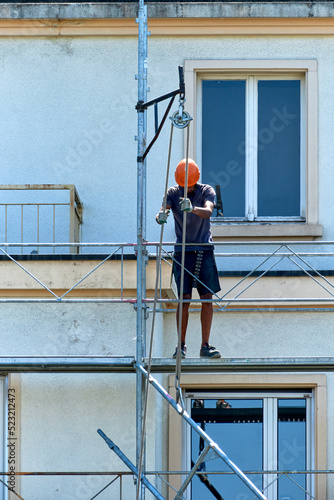 workers in safety uniform install reinforced steel scaffolding to renovate a facade in Geneva, Switzerland