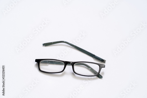 Broken reading glasses on white background