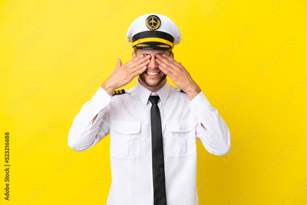 Airplane caucasian pilot isolated on yellow background covering eyes by hands Airplane caucasian pilot isolated on yellow background covering eyes by hands