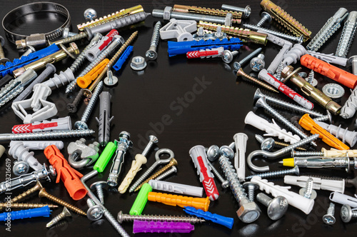 Different types of fasteners on a dark wood background. Front view. Place for text or logo.