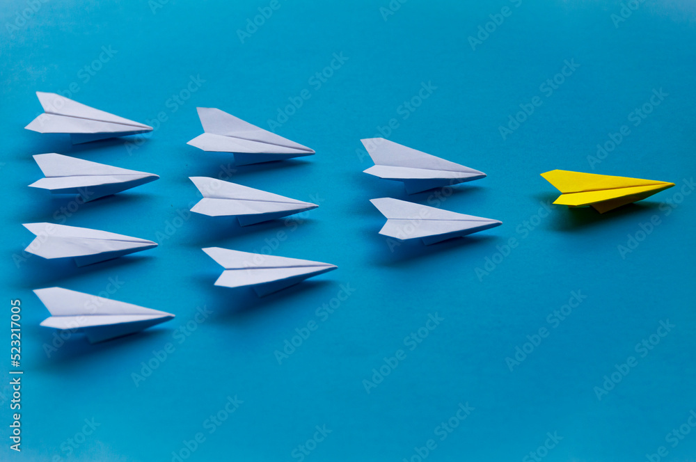 Naklejka premium Yellow paper plane origami leading white planes on blue background. Leadership skills concept
