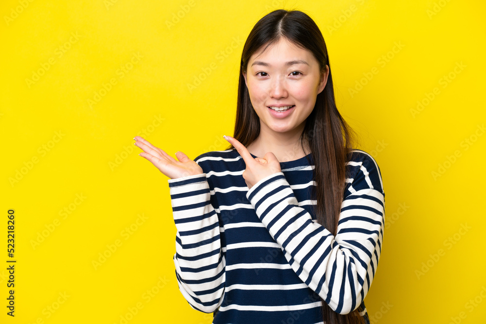 Young Chinese woman isolated on yellow background holding copyspace imaginary on the palm to insert an ad Young Chinese woman isolated on yellow background holding copyspace imaginary on the palm to insert an ad