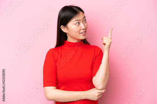 Young Chinese woman isolated on pink background pointing up a great idea © luismolinero