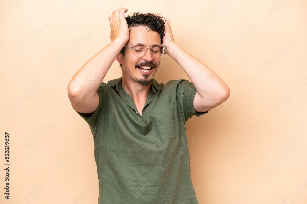 Young caucasian man isolated on beige background laughing Young caucasian man isolated on beige background laughing