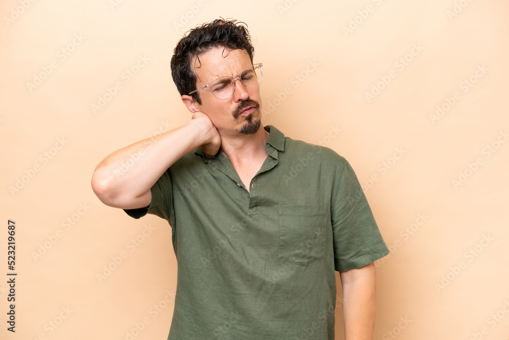 Young caucasian man isolated on beige background with neckache Young caucasian man isolated on beige background with neckache