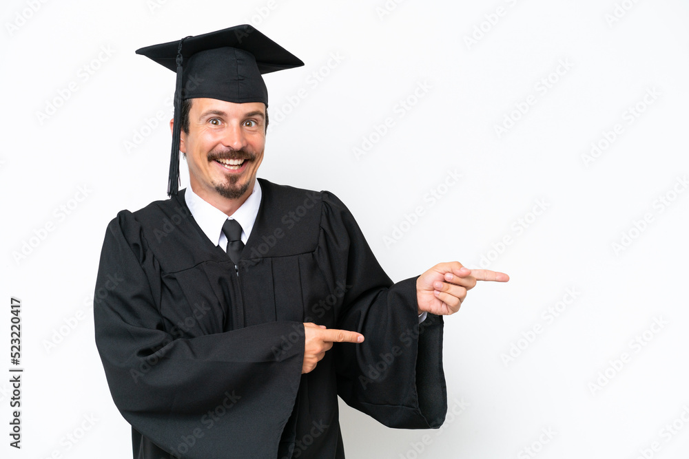 Young university graduate man isolated on white background surprised and pointing side Young university graduate man isolated on white background surprised and pointing side