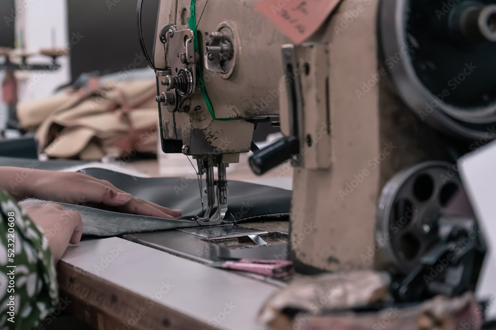 Fototapeta premium The seamstress sews on an old sewing machine, threads the fabric. Women's hands