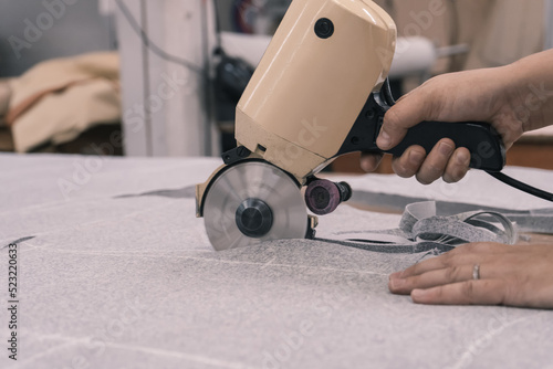 The cutter cuts the fabric with a disc cutting knife in the sewing workshop photo