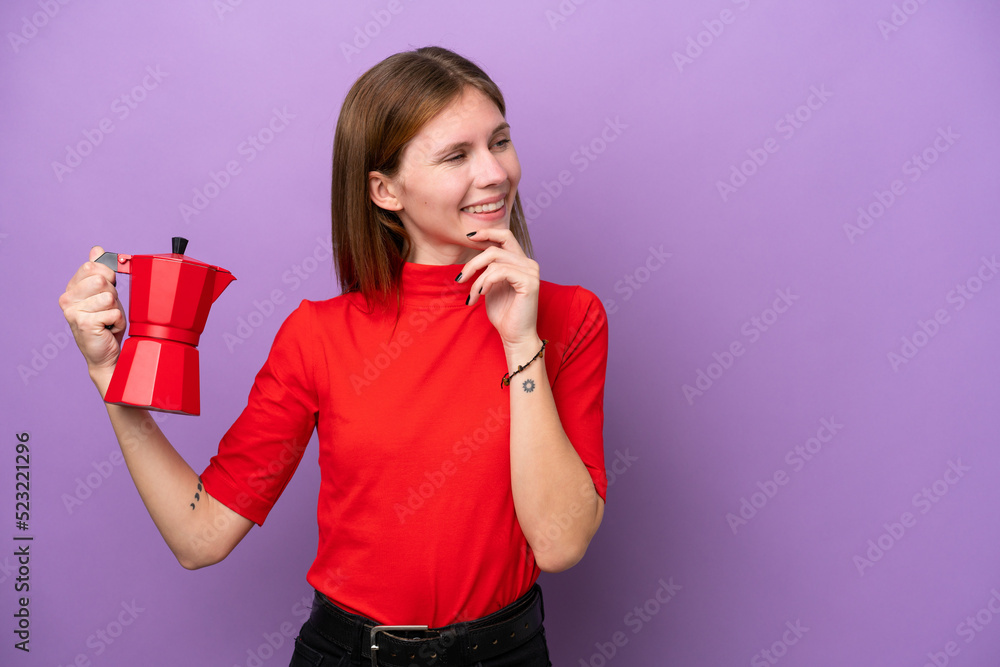 Young English woman holding coffee pot isolated on purple background thinking an idea and looking side Young English woman holding coffee pot isolated on purple background thinking an idea and looking side