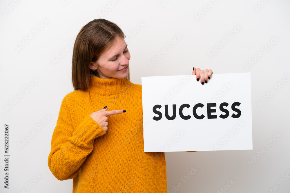 Young English woman isolated on white background holding a placard with text SUCCESS and pointing it Young English woman isolated on white background holding a placard with text SUCCESS and pointing it