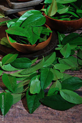 The picked green leaves are placed in a wooden bowl on a wooden cutting board